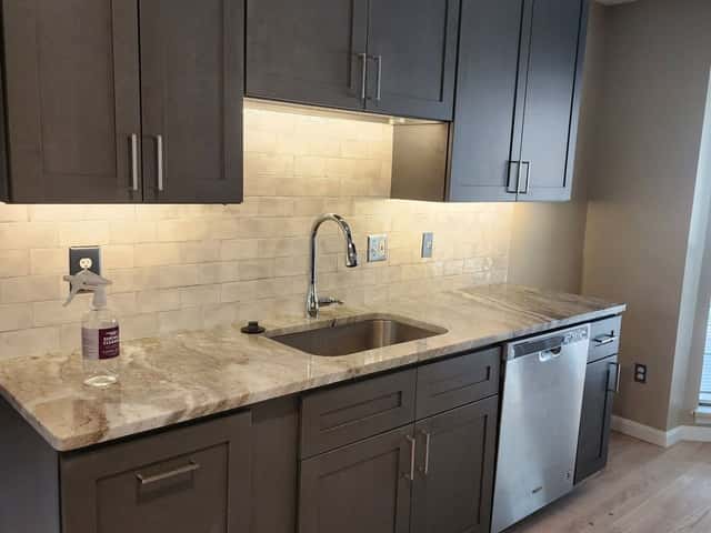 Kitchen remodel with dark shaker cabinets, a granite counter and stainless dishwasher
