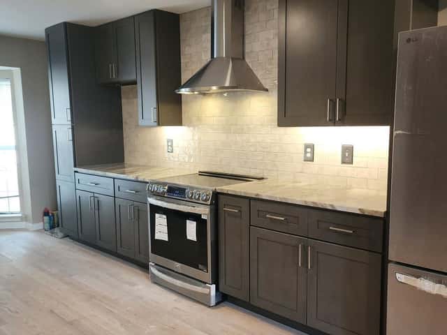 Galley kitchen renovation with dark cabinetry, subway tile backsplash and a stainless range hood