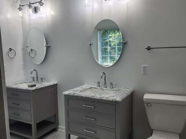 Bathroom with two grey vanities, marble tops and round mirrors