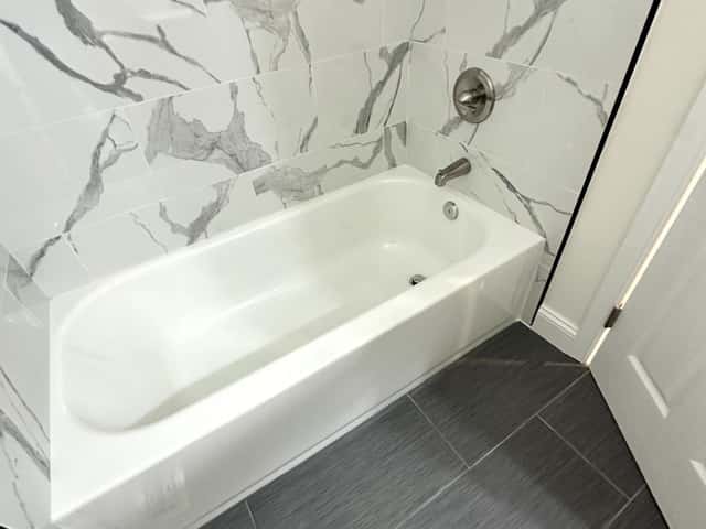 Tub and shower remodel with marble-look wall tile and black fixtures