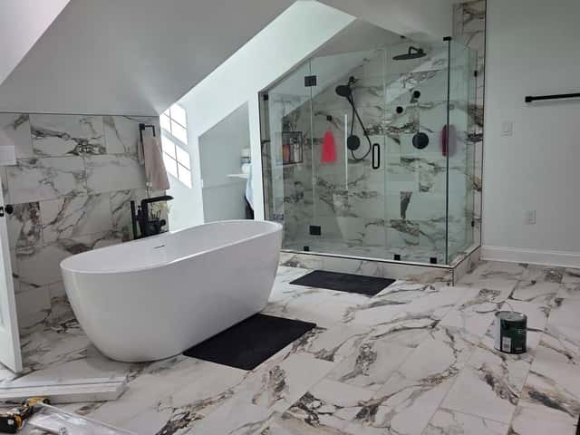 Primary bathroom with a freestanding soaking tub, glass shower and marble-look tile