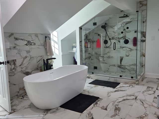 Freestanding tub and frameless glass shower in a marble-tiled bathroom remodel