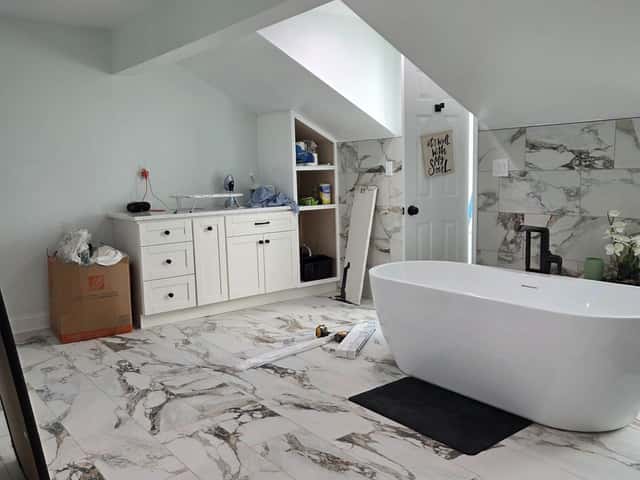 Attic bathroom conversion with a freestanding tub, white vanity and marble-look floor